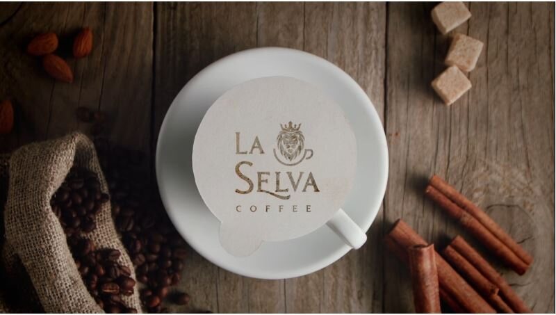 A La Selva Coffee cup on a saucer, surrounded by coffee beans and cinnamon sticks
