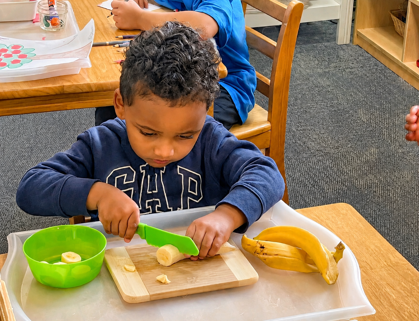A child slicing a banana